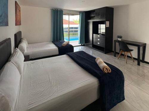 a bedroom with two beds and a desk and a television at Casa Balam Gladiolas in Cancún