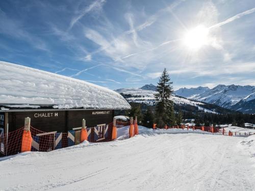a snow covered slope with an orange fence and a building at Chalet H XL in Königsleiten