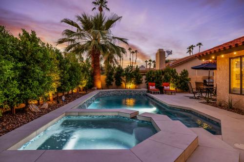 a swimming pool in a backyard with a palm tree at Azure Oasis-Saltwater Pool & Spa with Putting green! in Palm Desert