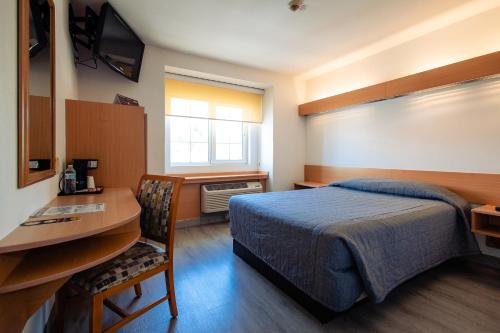 Un dormitorio con una cama y un escritorio y un escritorio. en Intercity Zapopan, en Guadalajara