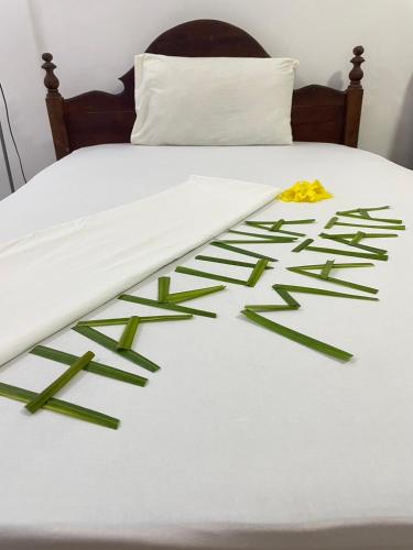 a bed with a white comforter with green leaves on it at Zanzllywood Uroa Beach Suites Hotel Apartment in Dikoni