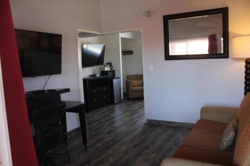 a living room with a couch and a desk and a television at Sunset Inn in Costa Mesa