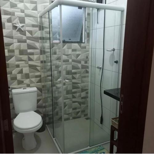a bathroom with a toilet and a glass shower at Casa com piscina! Descanso e Lazer in Itapoa