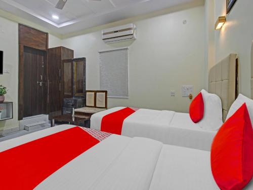 two beds in a room with red and white at Hotel O Mango Tree in Khammam
