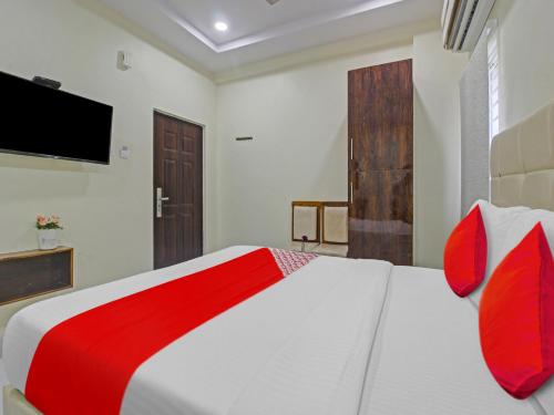 a bedroom with a bed with red pillows and a television at Hotel O Mango Tree in Khammam