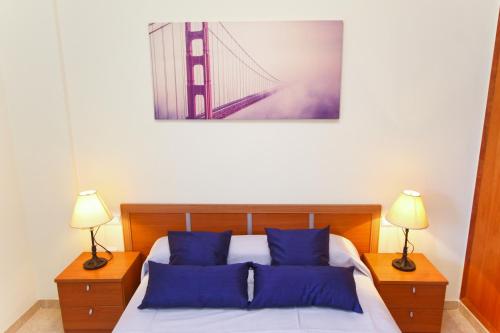 een slaapkamer met een bed met blauwe kussens en een brug bij Roura 2 Planetcostadorada in La Pineda
