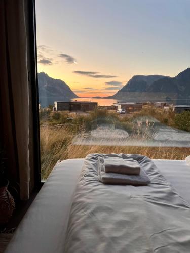 a bed with two towels on it in front of a window at Hoda Cabin - Luxury lodge with jacuzzi and sauna in Lyngværet