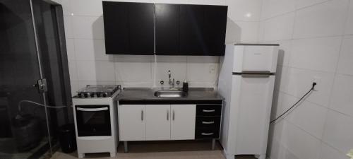 a small kitchen with a sink and a refrigerator at Casa 2 quartos com Garagem in Limeira