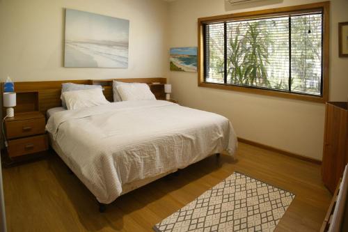 a bedroom with a bed and a window at Seabreeze Arches in Callala Bay