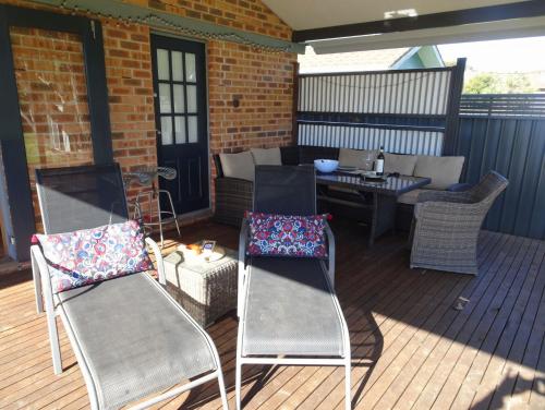 a deck with chairs and a table and a table and chairs at Sojourn - Culburra Beach in Culburra Beach