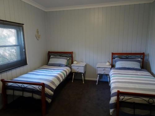 a room with two beds and a table and a window at Sojourn - Culburra Beach in Culburra Beach