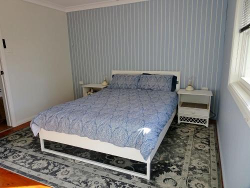 a bedroom with a bed with a blue comforter at Sojourn - Culburra Beach in Culburra Beach