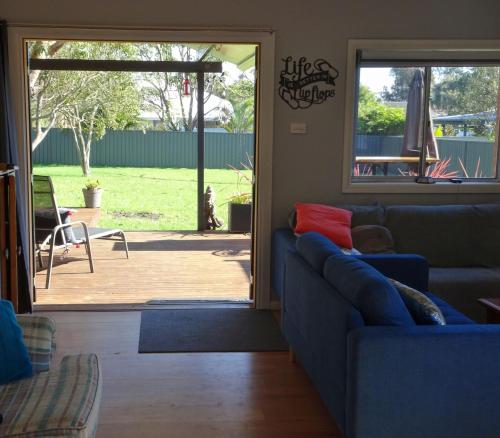 a living room with a couch and a sliding glass door at Sojourn - Culburra Beach in Culburra Beach