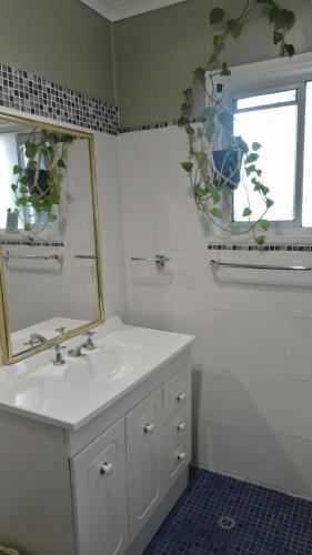 a bathroom with a sink and a mirror and a window at Sojourn - Culburra Beach in Culburra Beach