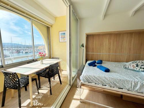 a bedroom with a bed and a table and a window at Les Terrasses du Port - VUE Port - Wifi - Parking - Clim in Leucate-Plage