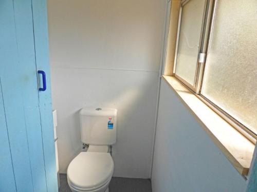 a small bathroom with a toilet and a window at Viv's Place in Greenwell Point