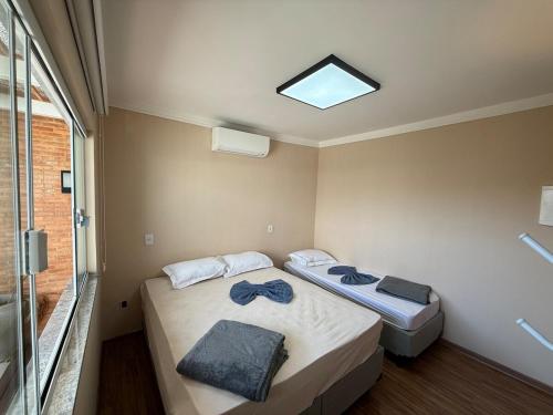 a bedroom with two beds and a skylight at Oka Tupis - casa de luxo para executivos c sauna e piscina aquecida in Santa Bárbara dʼOeste