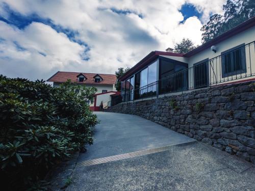 a house with a stone wall and a driveway at Casas de Pedra in Camacha