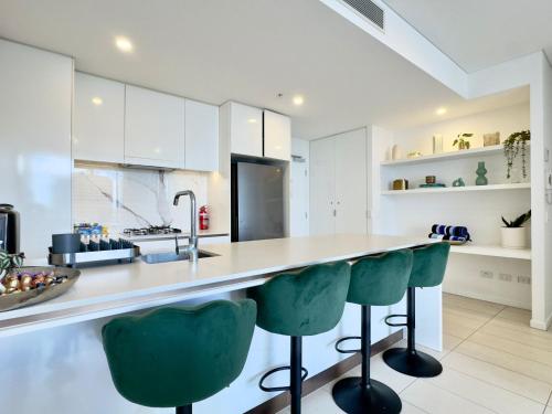 a kitchen with white cabinets and green bar stools at River View Apartment South Brisbane in Brisbane