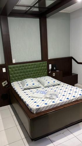 a bed with a green headboard in a bedroom at Hotel estrela da lapa in Sao Paulo