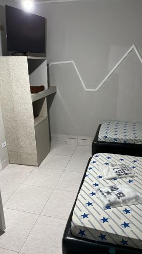 a room with two beds and a flat screen tv at Hotel estrela da lapa in Sao Paulo