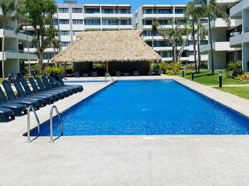 une piscine avec des chaises et un grand bâtiment dans l'établissement Acacia Resort, Nuevo Vallarta, à Nuevo Vallarta