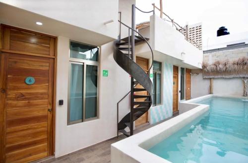a swimming pool with a spiral staircase next to a house at Casa Cielo Cancun in Cancún