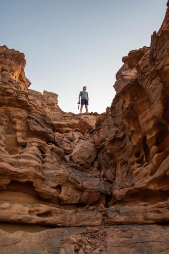 a man standing on top of a rocky cliff at Mars Land Luxury Camp in Wadi Rum