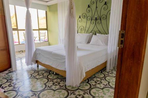 a bedroom with a bed with white sheets and a window at Hotel Bahia Del Faro in Guatapé