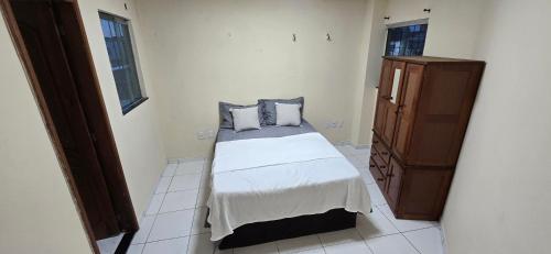 a bedroom with a bed and a wooden cabinet at Linda Casa 3 suítes in Belém