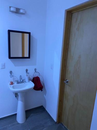 a bathroom with a sink and a mirror and a door at La PRIMAVERA APARTMENT IN CUERNAVACA in Cuernavaca