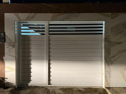 a white garage door in a stone wall at Casa Com Piscina em Itamaracá in Itamaracá