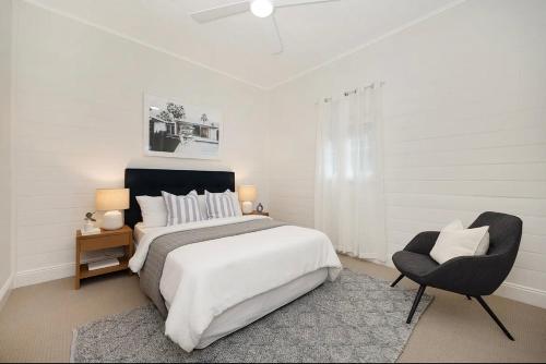 une chambre blanche avec un grand lit et une chaise dans l'établissement Historic CBD Miner's Cottage, à Brisbane