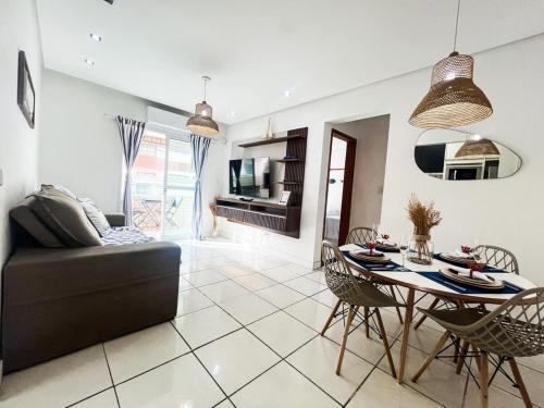 a living room with a couch and a table and chairs at Onda76 Ap temporada Praia Grande Beira Mar churrasqueira carvão in Praia Grande