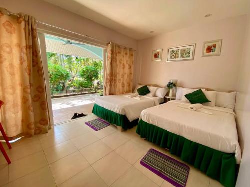 a bedroom with two beds and a large window at Camotes Seaside Tourist Inn - Camao Resort in San Francisco