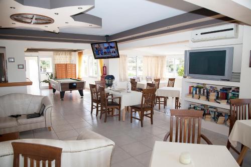 a restaurant with tables and chairs and a flat screen tv at Hotel Athinoula in Kefalos