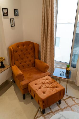 a brown chair and a stool in a living room at Elysium Grand Luxury Apartments Fronting Centaurus Mall Islamabad in Islamabad