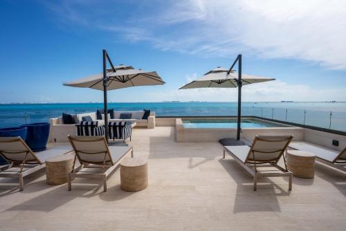 a patio with chairs and umbrellas overlooking the ocean at 5BR Luxury Beachfront Penthouse w/ Private Pool in Isla Mujeres