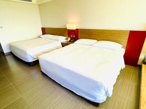 two beds in a hotel room with white sheets at Fullon Hotel LihPao Resort in Houli