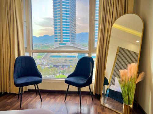 a room with two chairs and a mirror and a window at Elysium Grand Luxury Apartments Fronting Centaurus Mall Islamabad in Islamabad