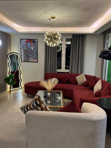 a living room with a red couch and a chandelier at Elysium Grand Luxury Apartments Fronting Centaurus Mall Islamabad in Islamabad