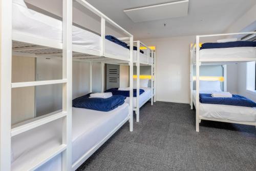 a room with three bunk beds in a dorm room at Hotel Give in Christchurch