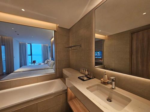 Un baño con bañera, lavabo y espejo. en Ala carte, en Ha Long
