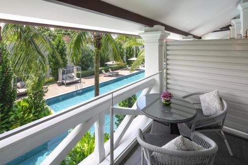 a balcony with a table and chairs and a swimming pool at The Barracks Hotel Sentosa by Far East Hospitality in Singapore