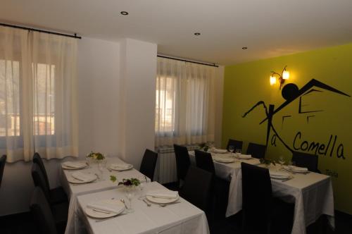 a dining room with white tables and black chairs at Casa Rural La Comella in Tirvia