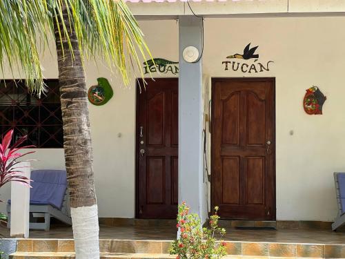a building with two wooden doors and a palm tree at Hostel Sunset Villas Popoyo in Popoyo