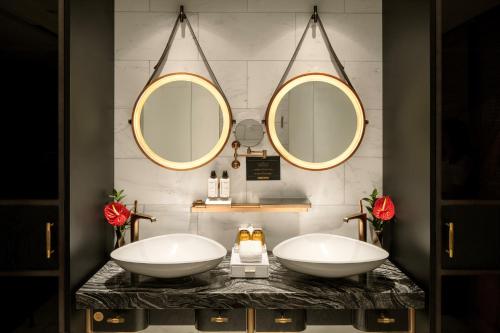two sinks in a bathroom with two mirrors at The Barracks Hotel Sentosa by Far East Hospitality in Singapore