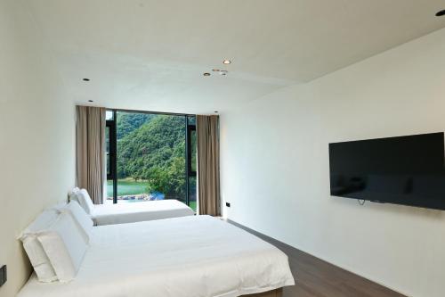 a bedroom with two beds and a flat screen tv at The Lake View Deyishe Resort in Thousand Island Lake in Thousand Island Lake