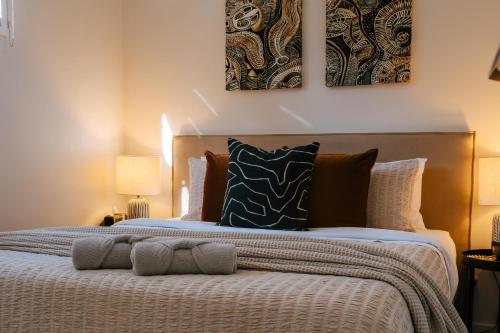 a bedroom with a bed with two paintings on the wall at The Waratah House - Modern Coastal Retreat near Cafes & Beach in Mona Vale