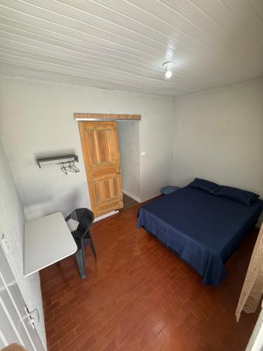 a bedroom with a bed and a table and a door at Brisa Suítes in Rio Verde